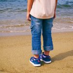 海を前に砂浜に立つ男の子の後ろ姿