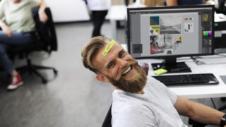 職場のデスクで笑う男性の画像